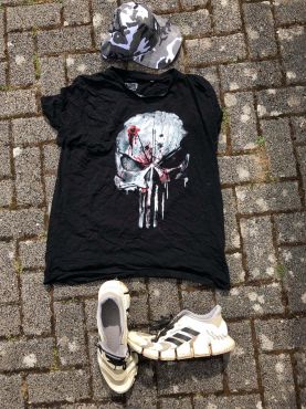 Kleidung des unbekannten Radfahrers: Schwarzes T-Shirt mit Aufdruck, weiße Turnschuhe und Mütze mit Tarnmuster